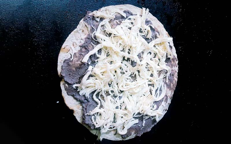 Encuadre al detalle de preparación de una tlayuda con queso